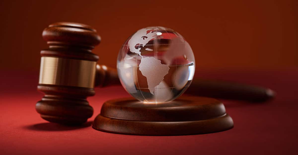 Como capa da matéria “Direito Internacional: Oportunidades e Desafios”, vemos um martelo de juiz ao lado de um globo terrestre.