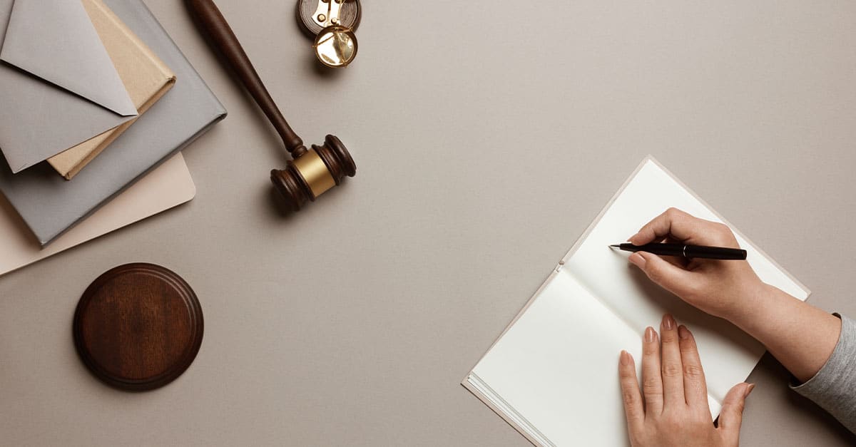 Como capa da matéria “7 maneiras para avaliar oportunidades no mundo jurídico”, temos a visão superior de uma mesa mostrando alguém fazendo anotações e um martelo de juiz.